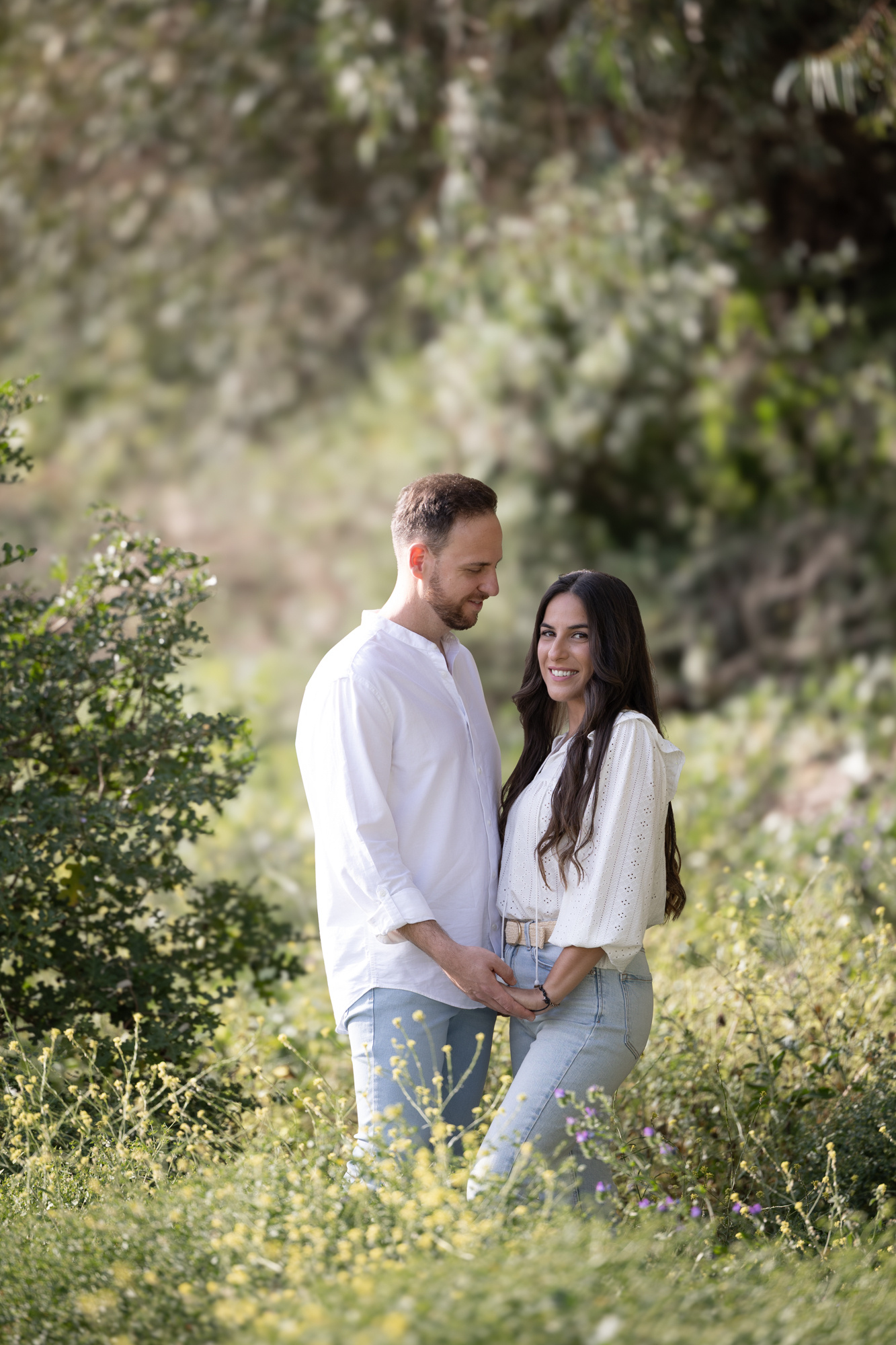 Novios tomados de la mano entre flores en su sesión preboda en Andalucía