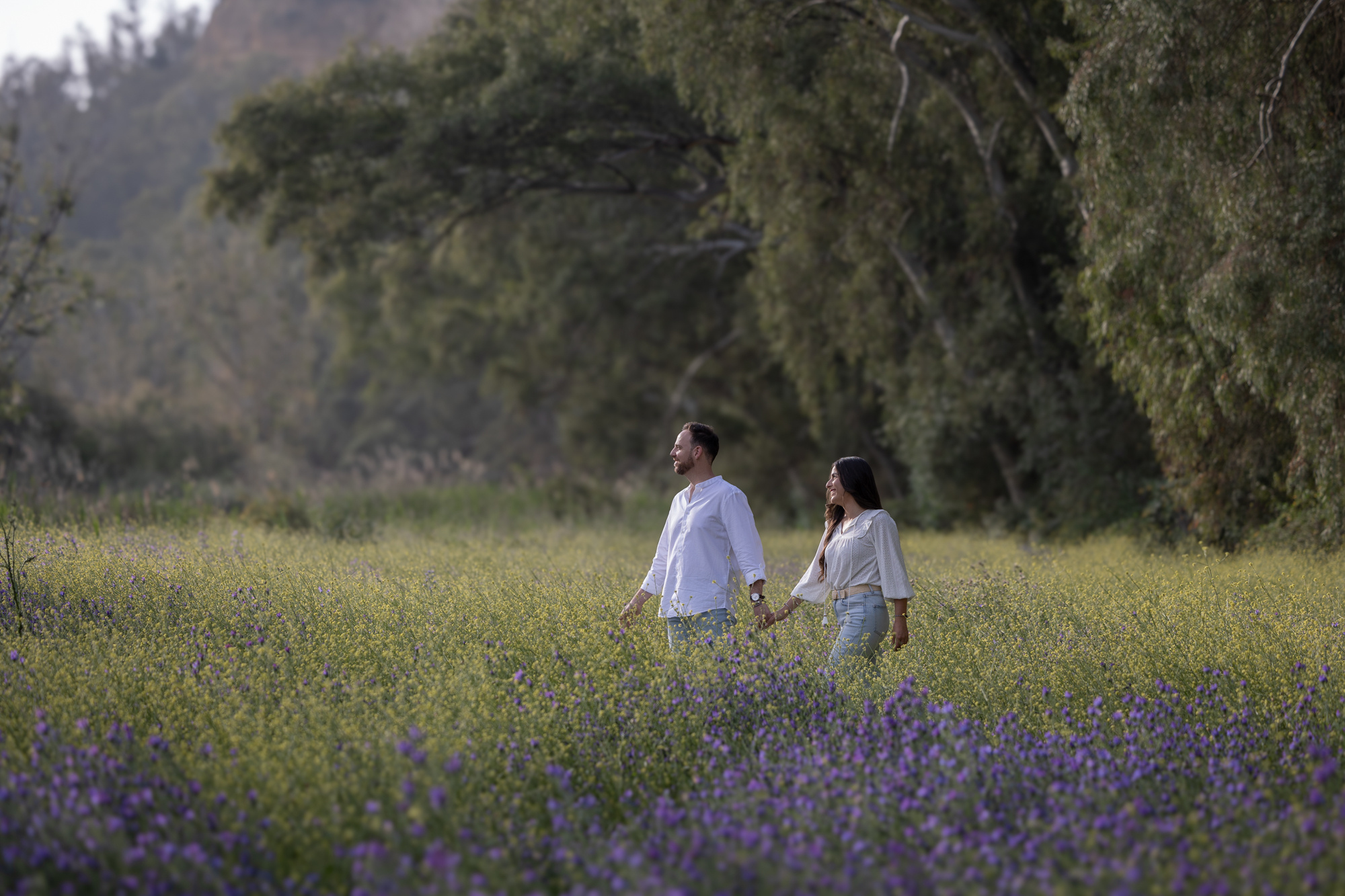 Pareja paseando por un campo de flores durane su sesión preboda en Andalucía