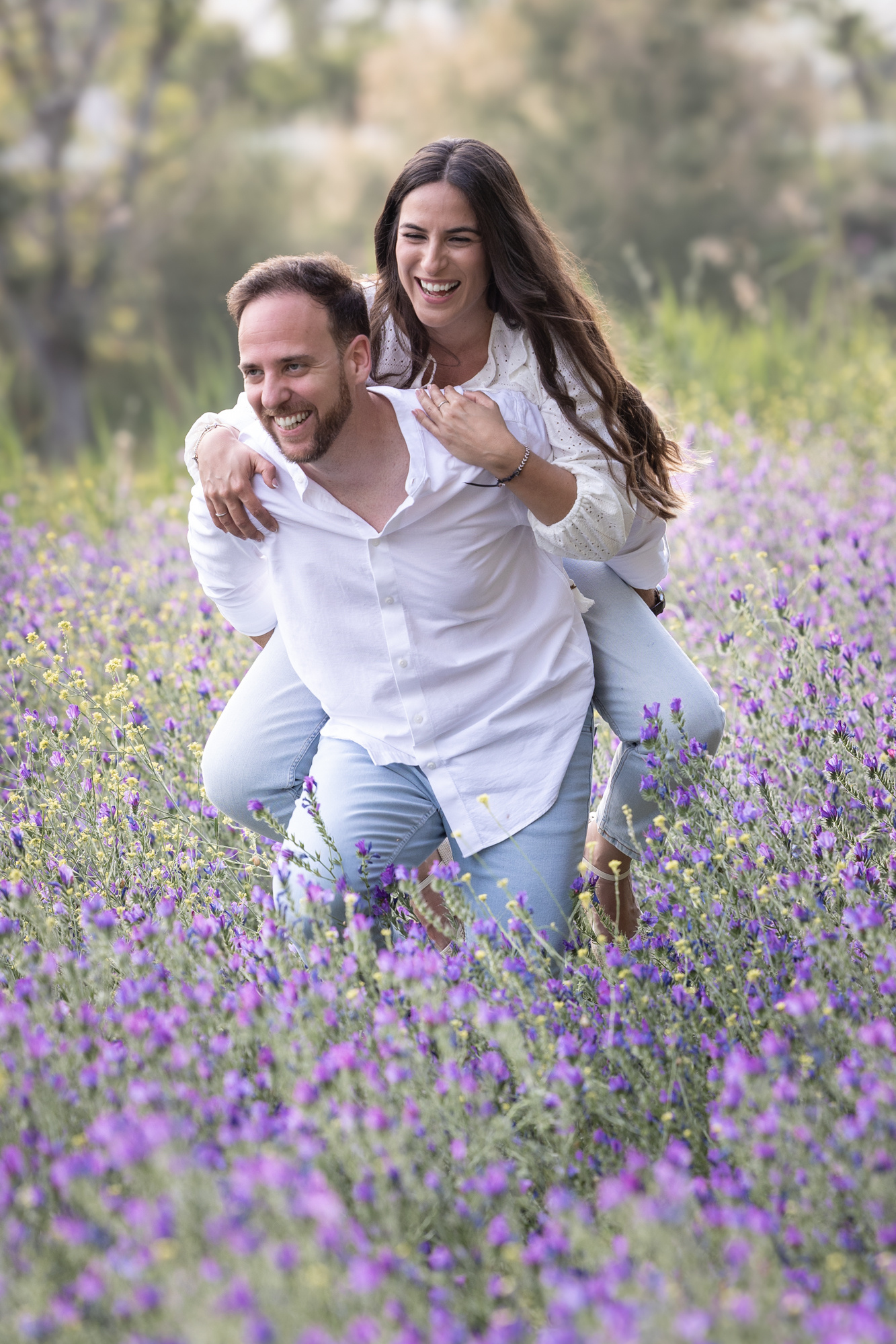 Novios jugando y riendo en un campo de flores, preboda en Cádiz
