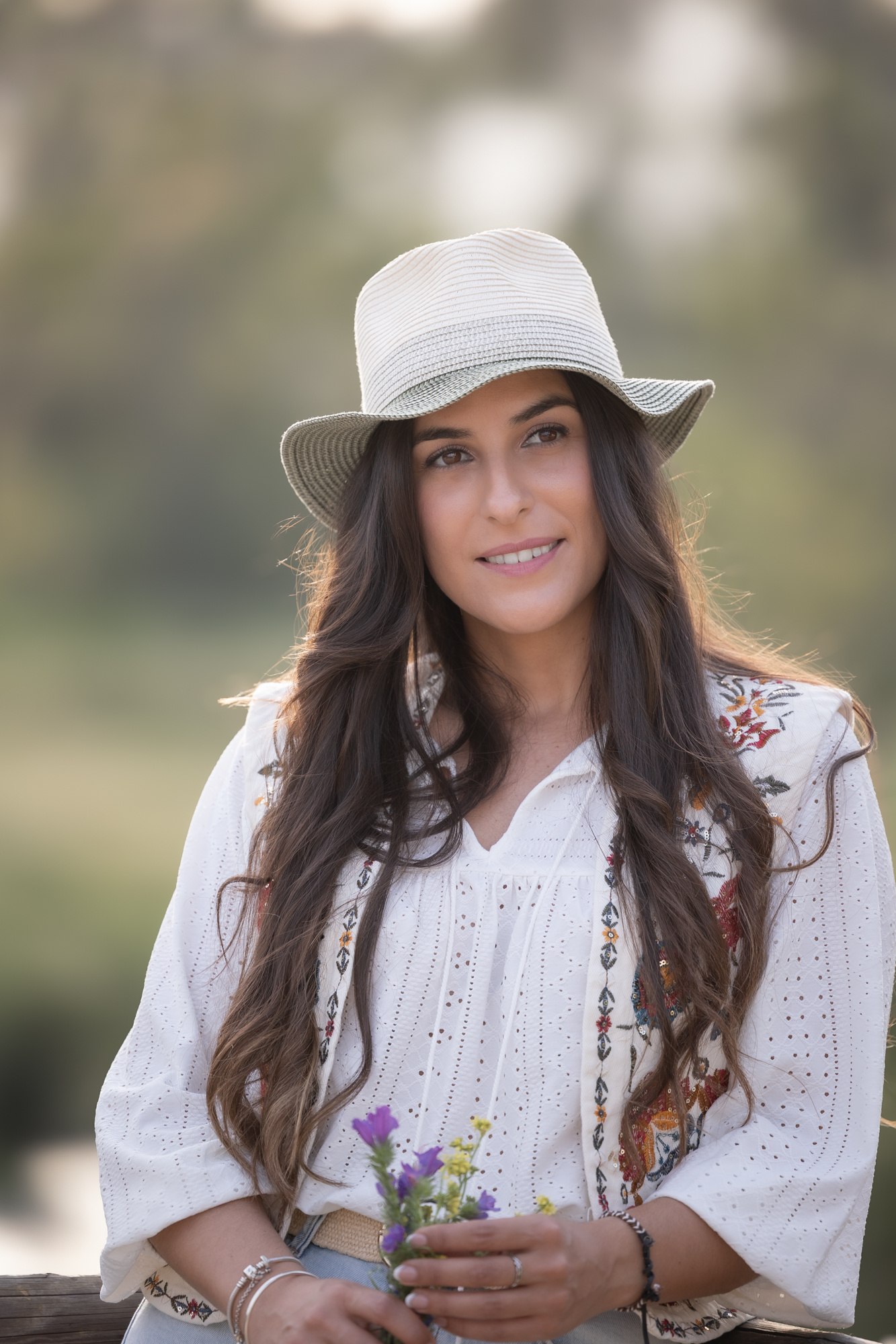 Lidia posa con un sombreo y flores en las manos. Sesión preboda Cádiz