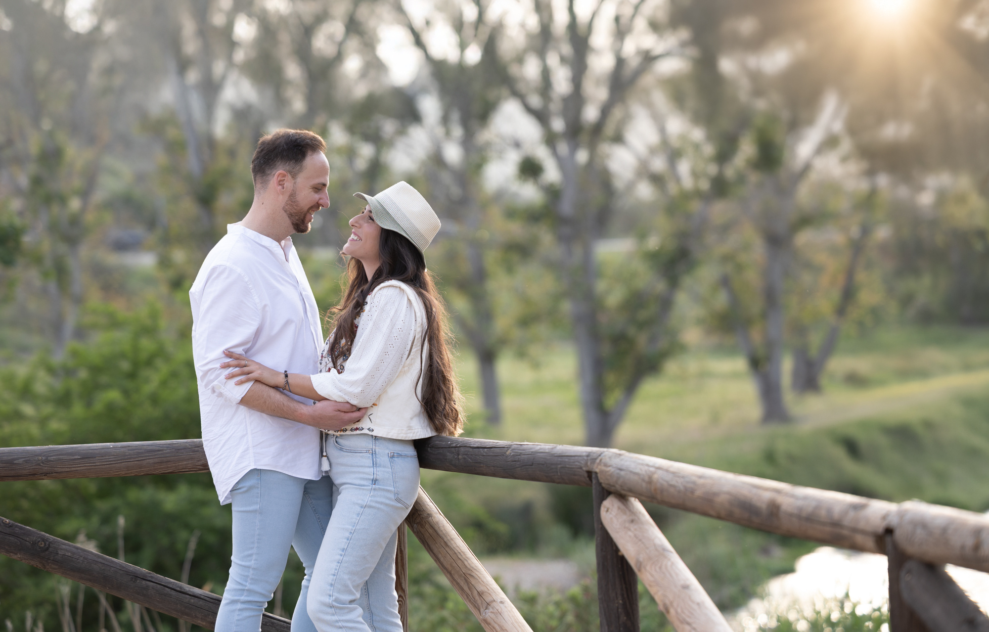 Paraja de novios mirándose en un puente de madera y sol a contraluz. Sesión Preboda Cádiz