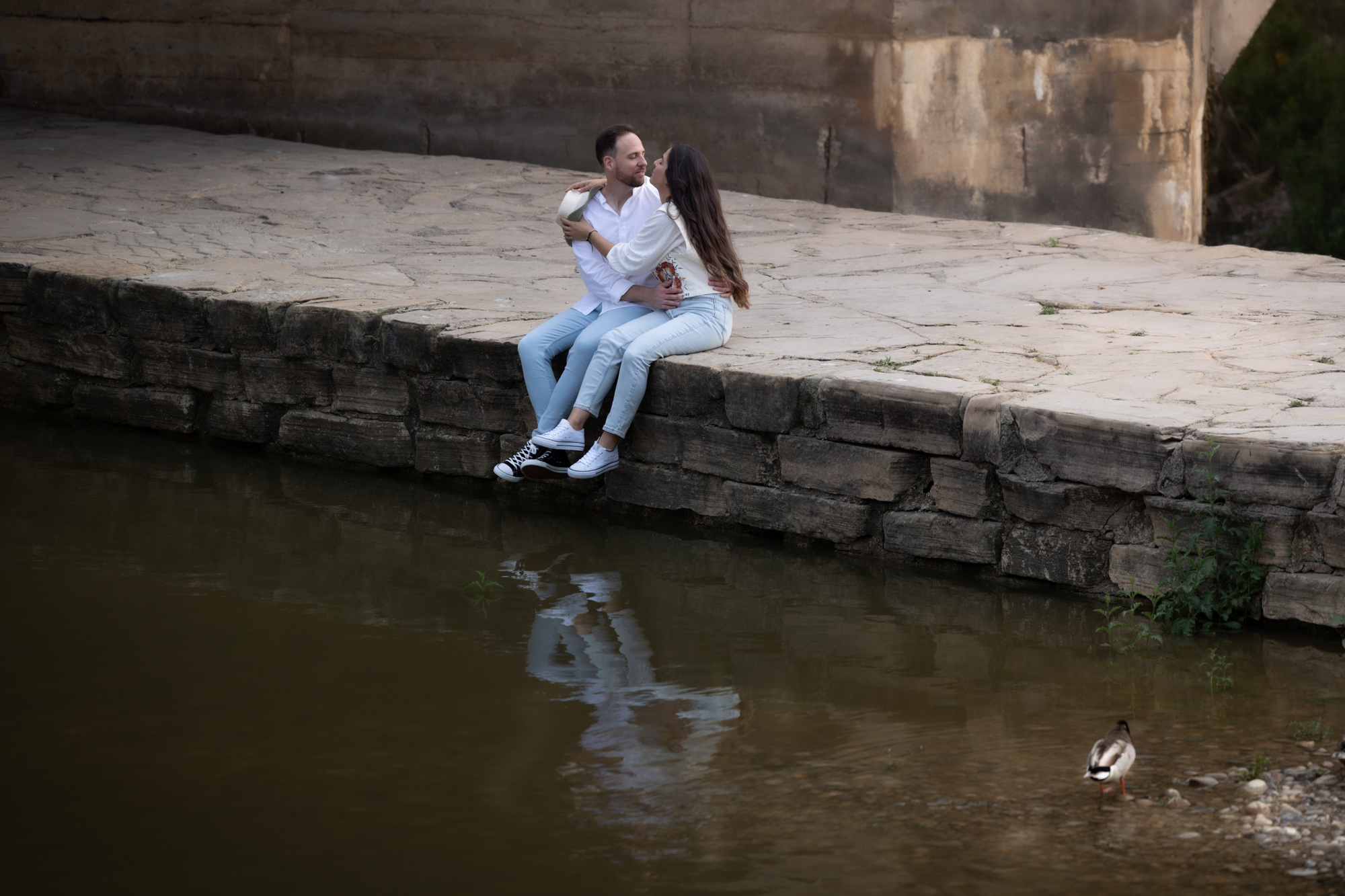 Lidia y Gabriel sentados junto a un río durante la sesión preboda