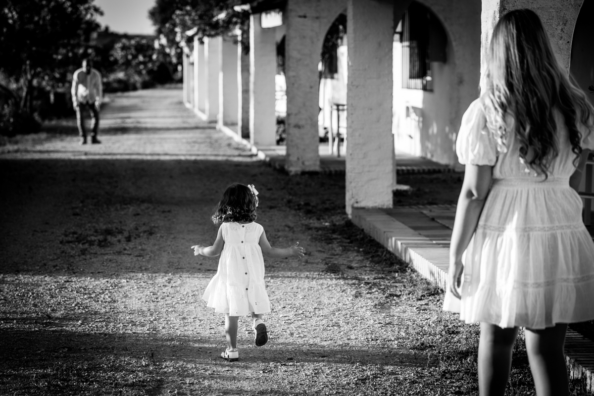 blanco y negro de una mujer, niña pequena y el padre jugando en unos bungalows del hotel de la Molinera en Arcos de la Frontera
