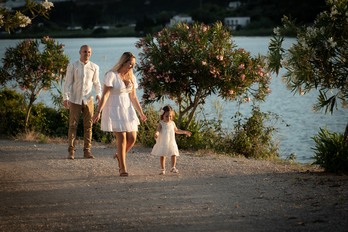 Mujer, un hombre y una niña de cuerpo entero paseando junto a un lago.