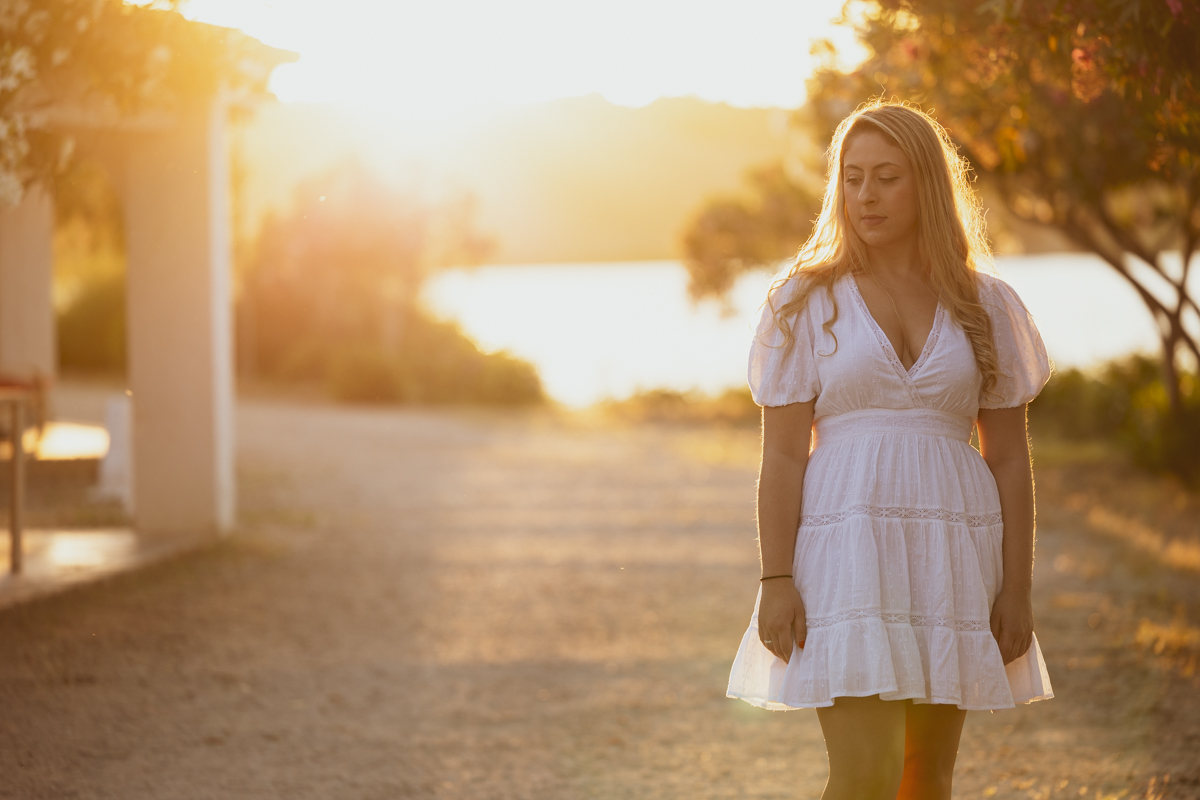 Mujer de mediana edad, de pelo rubio, vestido blanco, posa de medio cuerpo junto al lago de Arcos