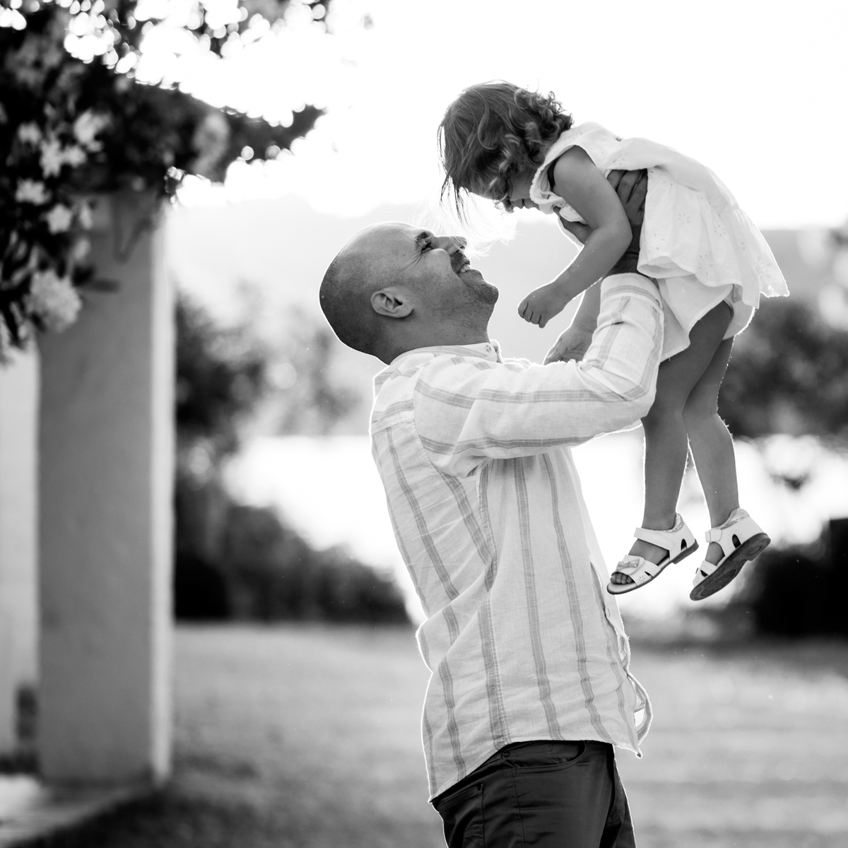Blanco y negro de un padre sonriente levanta a su hija pequeña en brazos