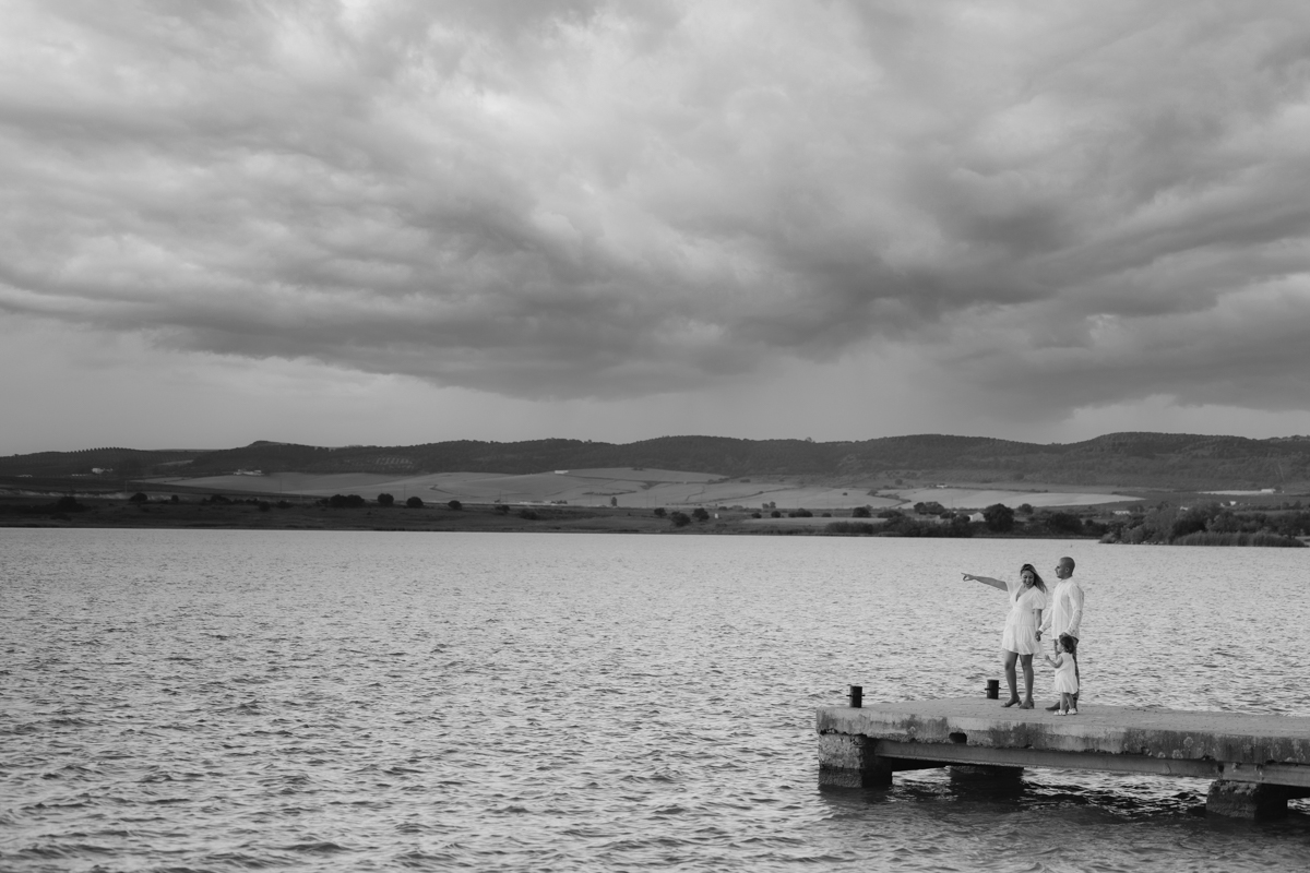 Familia compuesta por una mujer, hombre y niña de dos años, caminan al atardecer junto al algo de Arcos