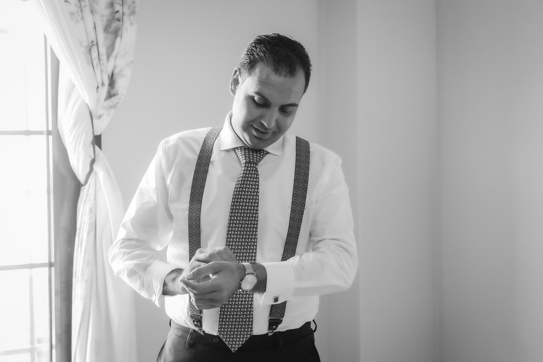 blanco y negro de Manuel colocándose los gemelos en la camisa