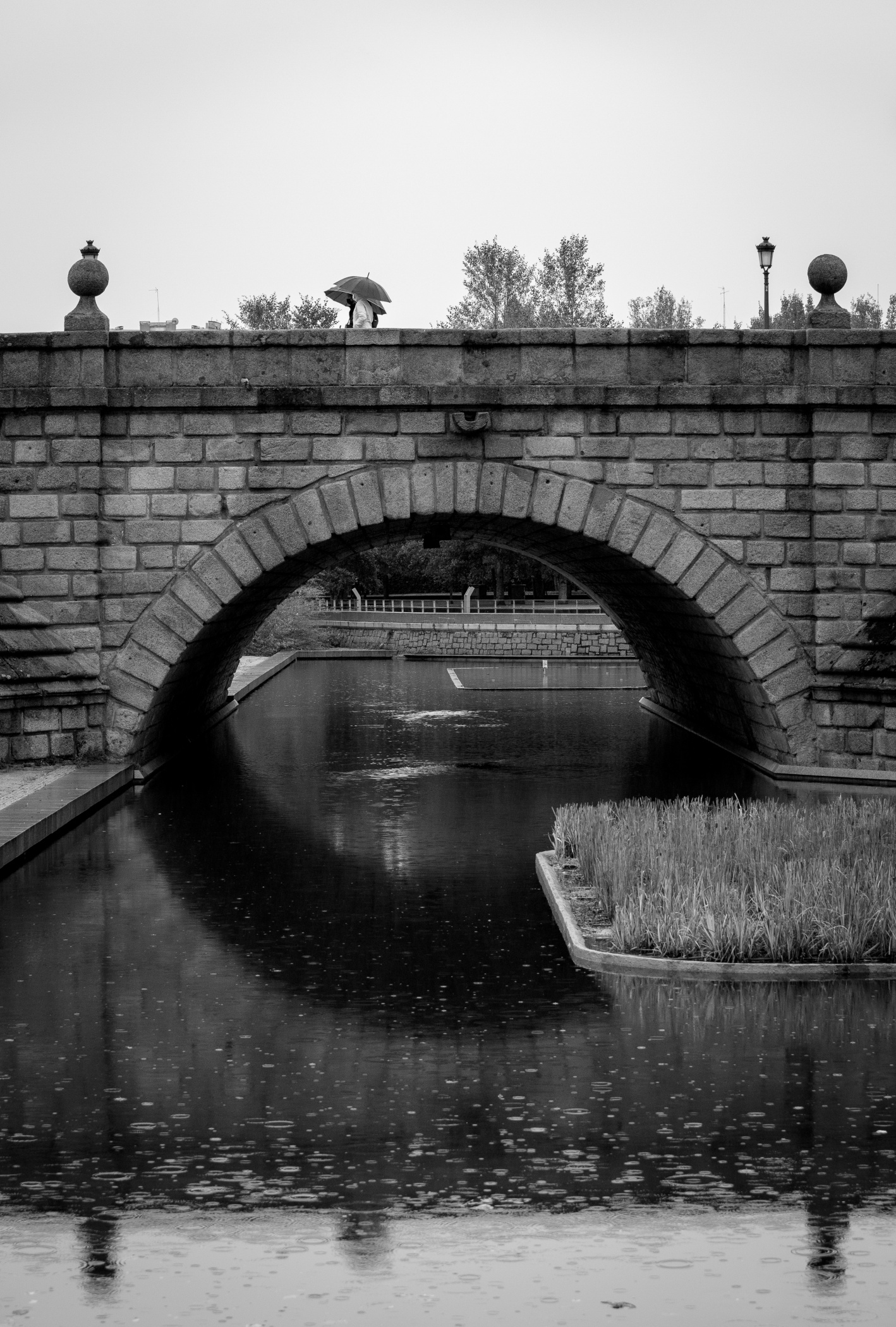 Dos personas con paragüas pasando por un puente sobre un río